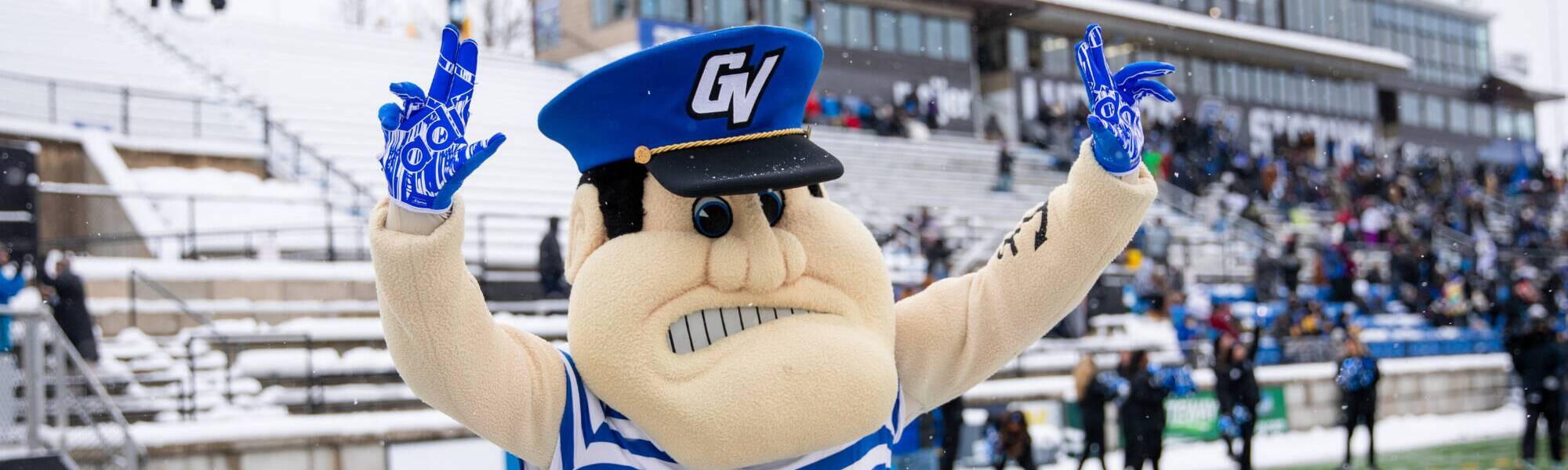 louie the laker holding up two anchor up signed on lubber's stadium field during a football game with snow in the backgroud